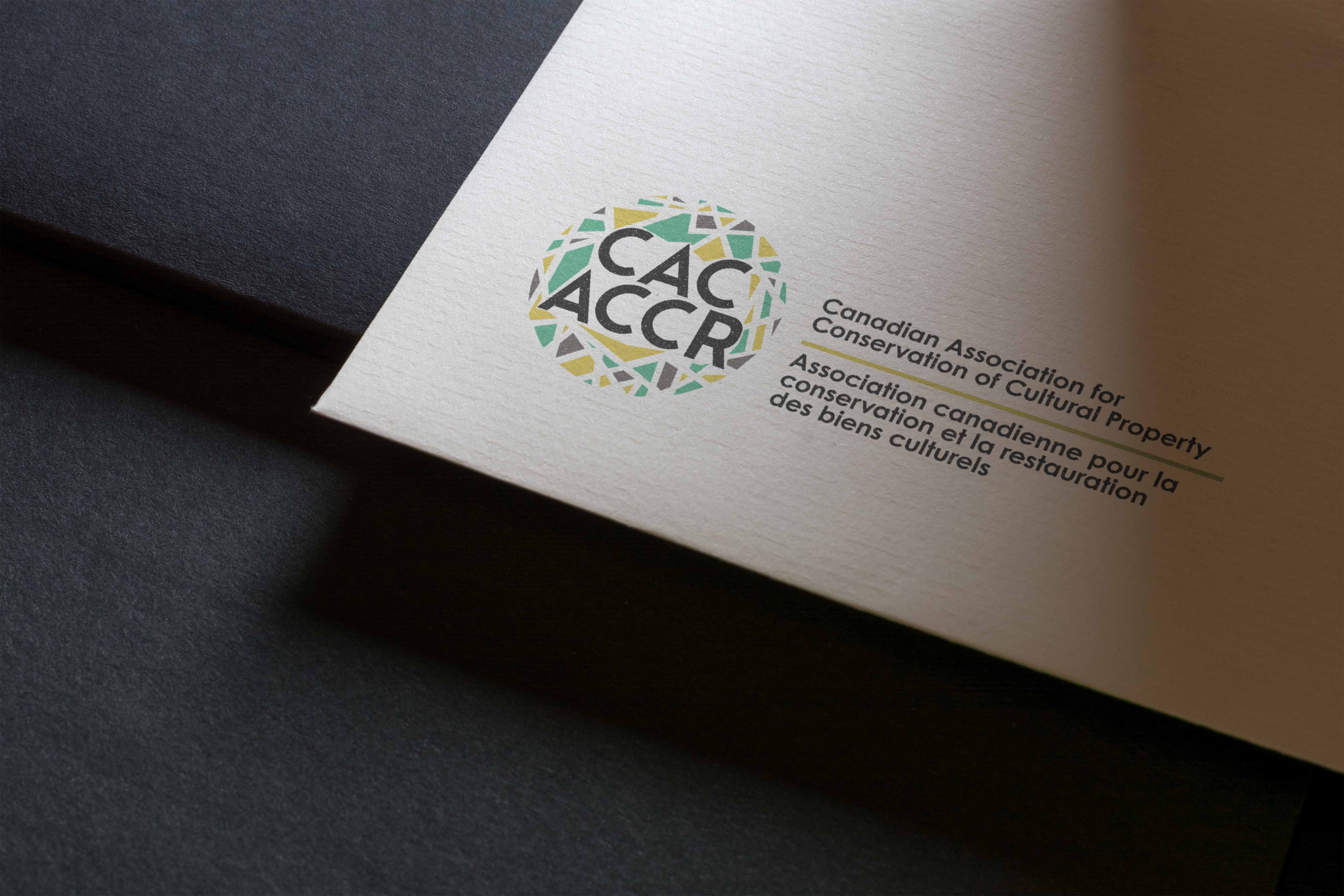 Mockup of rebranded colour logo for CAC-ACCR on stationery. Showing bottom lefthand corner on black background.