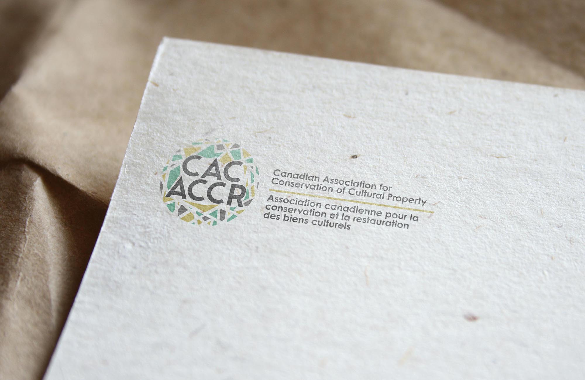 001 CAC Logo Mockup of rebranded colour logo for CAC-ACCR on stationery. Showing top left-hand corner on beige background.